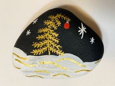 a painted rock with snowflakes on it and a christmas tree in the middle