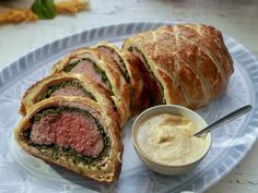 a plate with some meat and bread on it next to a bowl of dipping sauce