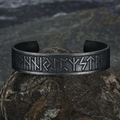 a black bracelet with the word viking on it, sitting on top of a rock