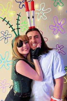 a man and woman standing next to each other in front of a wall with decorations on it