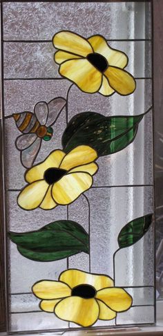 a stained glass window with yellow flowers and a bee