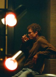 a man sitting on a chair drinking from a bottle in front of a traffic light