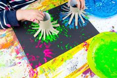 the child is painting on paper with their hands