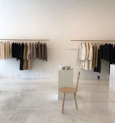 an empty room with clothes hanging on racks and a chair