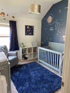 a baby's room with a blue rug on the floor and a space theme painted on the wall