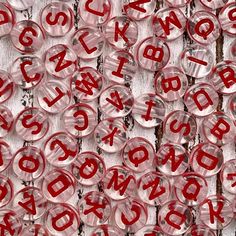 red letters and numbers are arranged in rows on a white wooden surface, with small circles around them