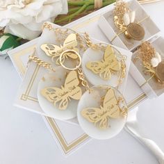 three personalized butterfly key chains on top of each other next to a bouquet of flowers