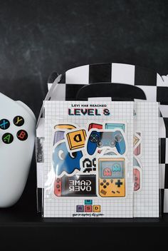 a nintendo wii game controller next to a box with stickers on it and a black and white checkered bag