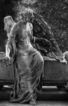 an angel statue sitting on top of a stone bench