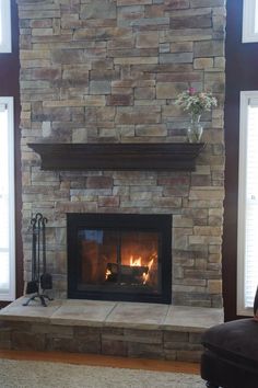 a living room with a stone fireplace and two windows