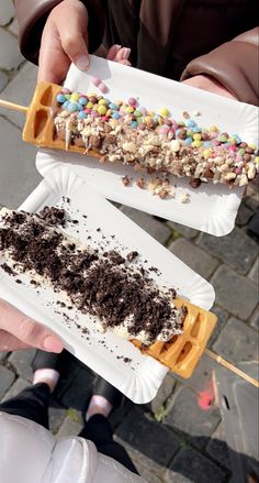 two people are holding waffles with chocolate and marshmallows on them