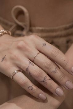 a woman's hand with three different tattoos on her fingers and the other finger