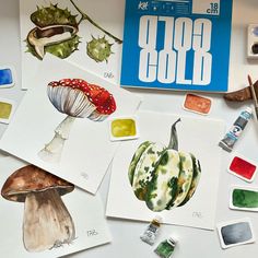 several different types of mushrooms are on the table next to paint and watercolors