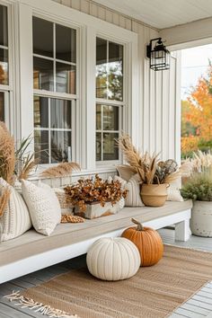 the front porch is decorated with pumpkins and plants