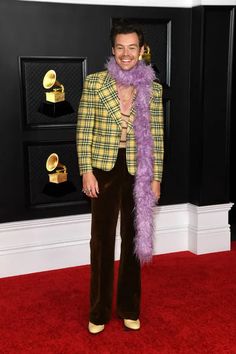 a man in a yellow jacket and purple scarf on the red carpet at an awards event