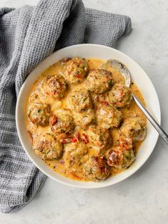 a white bowl filled with meatballs and sauce