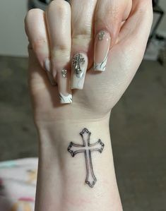 a woman's hand with a cross tattoo on her wrist and the other arm