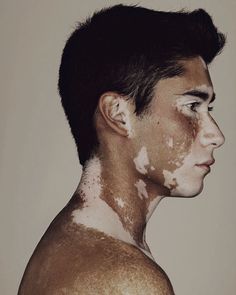 a man with white paint all over his face and chest, looking to the side