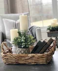 a wicker basket filled with books and candles on top of a table in front of a window