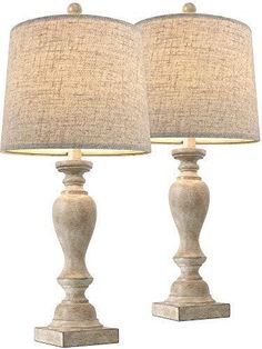 two lamps are sitting next to each other on a white surface with a beige shade