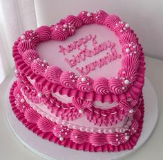 a heart shaped birthday cake with pink frosting