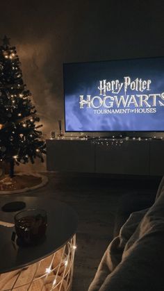 the hogwarts logo is displayed in front of a christmas tree and large screen