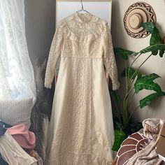 a wedding dress hanging on a clothes rack next to a plant and other items in front of a window