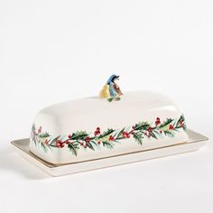 a white platter with a bird on it and holly garland around the edge, sitting on top of a plate