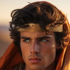 a young man wearing a gold head piece and a scarf around his neck is staring at the camera