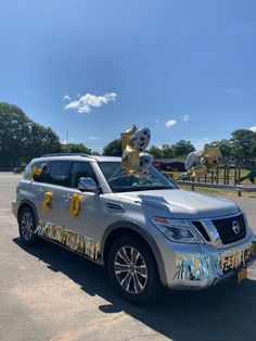 a silver suv with balloons and streamers on the roof parked in a parking lot