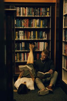 two people sitting on the floor in front of a book shelf with bookshelves