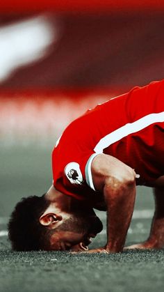 a soccer player with his head down on the ground while holding his hands behind his head