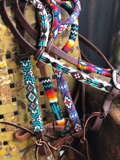 several colorful braided horses bridles on top of a yellow horse trailer with brown leather straps