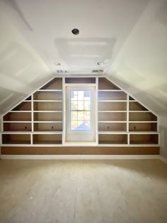 an empty room with shelving in the middle and a window on the far wall