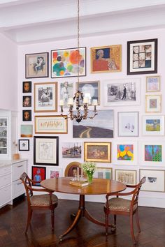 a dining room table surrounded by pictures on the wall