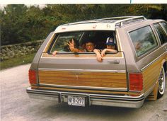 a car that is sitting in the street with someone waving from it's window