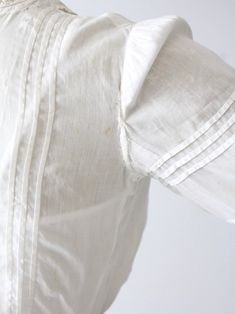 An Edwardian era blouse. The small white cotton blouse features intricate white embroidery. Sweet little buttons closes the blouse down the back. There is lace trim at neck, pin tuck detailing, and three-quarter sleeves. CONDITION In good antique condition. There is a worn spot on back of waistband. Holes do not go all the way through. There is some thinning and wear to the left shoulder. SIZE & MEASUREMENTS Approximate SizeXS Bust32 inch ...81.3 cm Length13.5 inch ... 34.3 cm Shoulders15.5 Victorian Cotton Fitted Blouse, Fitted Victorian Cotton Blouse, White Fitted Victorian Blouse, Fitted White Victorian Blouse, Victorian White Cotton Top, Victorian Style White Cotton Top, Fitted White Blouse With Covered Buttons, White Fitted Blouse With Covered Buttons, Cotton Tops With Pintucks For Daywear