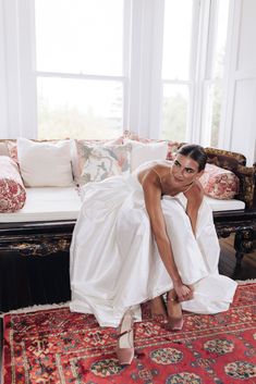 a woman laying on top of a red rug in front of a couch with pillows