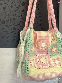 a crocheted handbag hanging on a wall with flowers and leaves in it