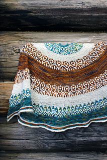 a crocheted shawl is hanging on a wooden wall next to a piece of wood