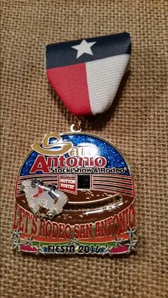 two medals are sitting on top of a cloth covered surface, one has a texas state flag and the other is a map