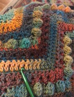 a crocheted blanket with a green hook on it