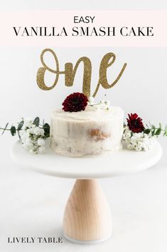 a cake on a white plate with the word one spelled out in gold letters and flowers