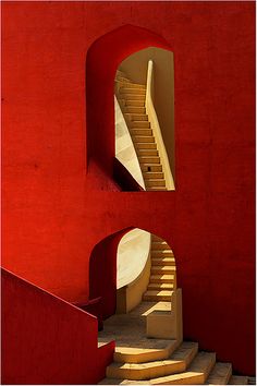 a red building with stairs leading up to the second floor and another staircase in front of it