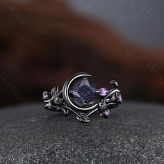 a ring that is sitting on top of a rock with leaves and flowers around it