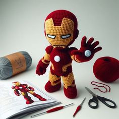 a crocheted iron man doll next to yarn and scissors