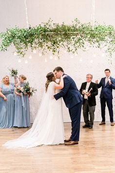 a bride and groom kissing in front of their wedding party