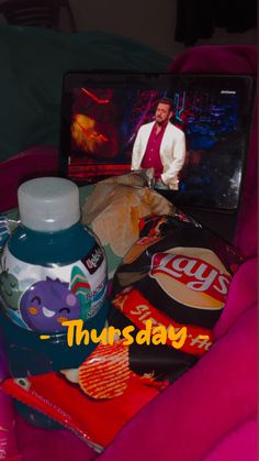 a laptop computer sitting on top of a bed covered in food and drink bottle next to it