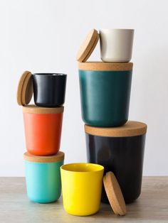 four cups stacked on top of each other with lids and wooden spoons in front of them