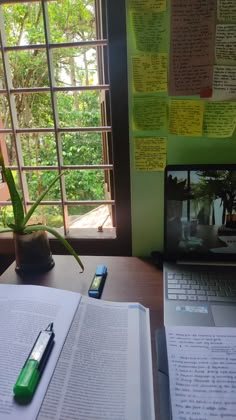 an open book sitting on top of a desk next to a laptop computer and a pen